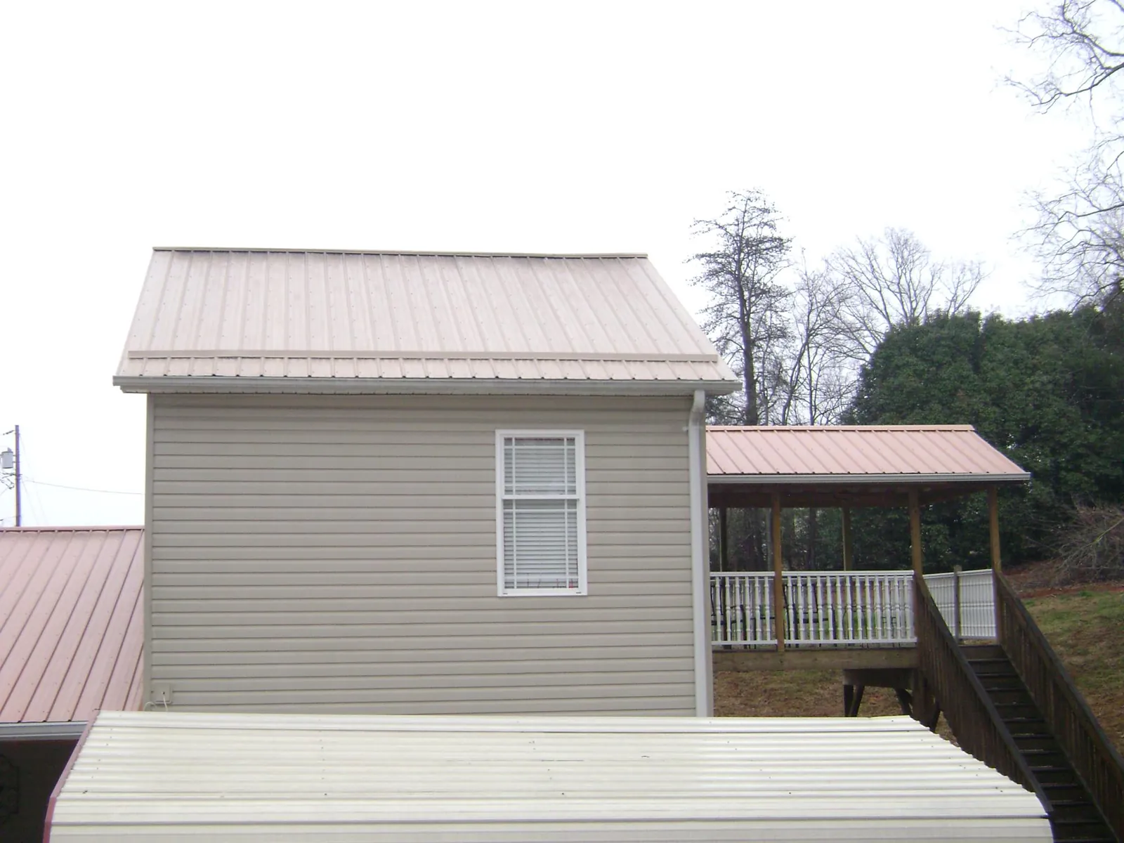 Tan metal roofs on a two story addition and attached porch, from a Roof Replacement job in Mount Laurel
