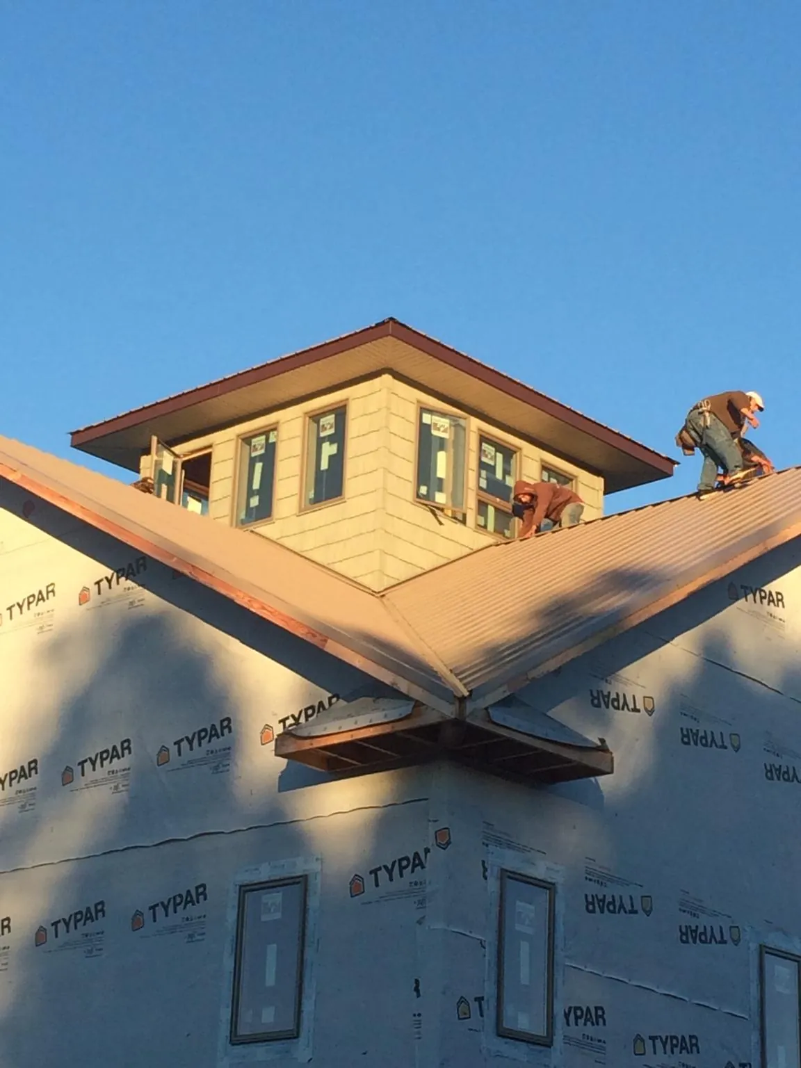 Roofers working around a rooftop cupola on a new metal roof at sunset — Roof Waterproofing in Mount Laurel by Roofing Brothers